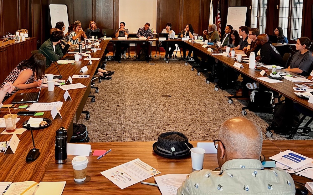people sitting around a square table in a conference room